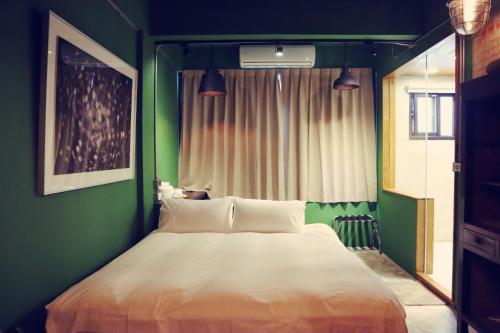 a bedroom with a large bed with a green wall at Travel Charger Hostel in Hualien City