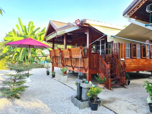 a wooden house with an umbrella and some plants at Lampang Hideaway Guesthouse in Lampang