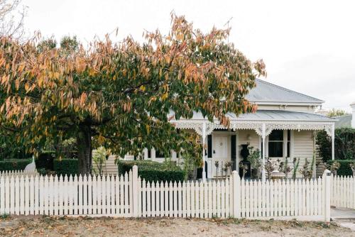 a white picket fence in front of a white house at Carrington House Daylesford in Daylesford