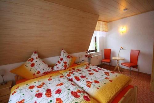 a bedroom with a bed and two red chairs at Ferienwohnung-Panoramablick in Neudorf