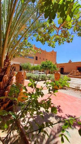 a building with a bunch of chairs and palm trees at Hotel Kasbah Ennakhile in Nkob