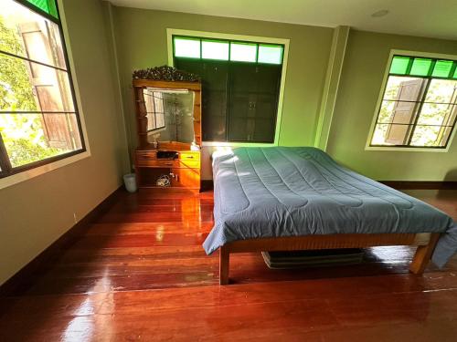 a bedroom with a bed and a dresser and two windows at BanLomLak in Sukhothai