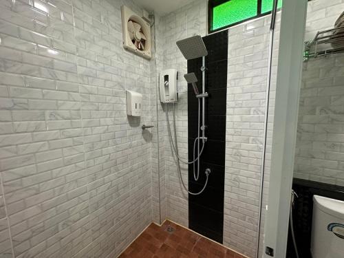 a shower in a bathroom with a white brick wall at BanLomLak in Sukhothai