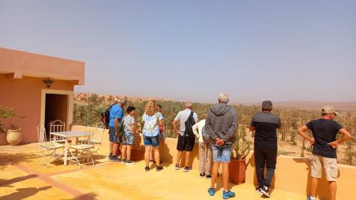 a group of people standing on a porch looking at a view at Hotel Kasbah Ennakhile in Nkob