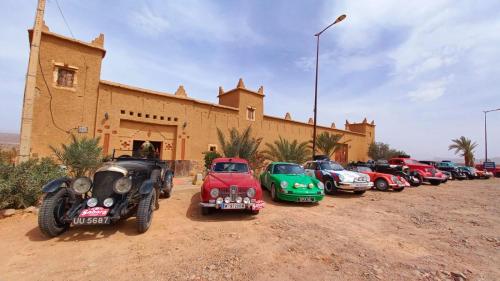 a row of cars parked in front of a building at Hotel Kasbah Ennakhile in Nkob