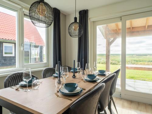 een eettafel met stoelen en een groot raam bij Modern holiday home by the sea with sauna in Scherpenisse
