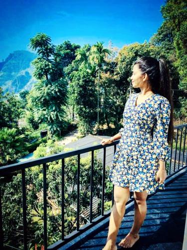 a woman in a floral dress standing on a bridge at Poomaz Peace Palace in Ella