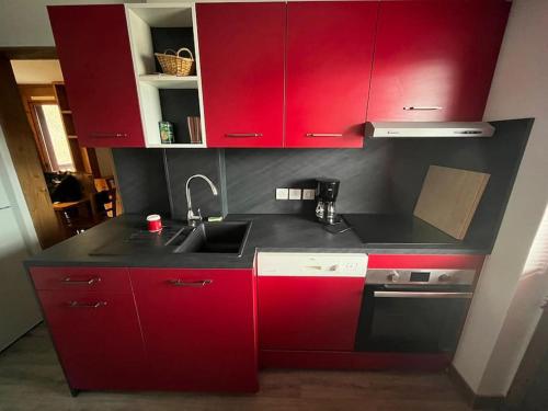 a kitchen with red cabinets and a sink at Superbe Appartement à Montchavin in Montchavin