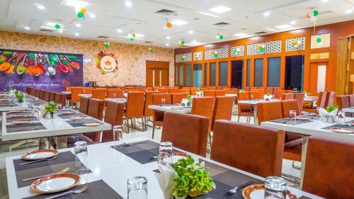 jadalnia ze stołami i krzesłami w restauracji w obiekcie Hotel Ambicas Grand w mieście Visakhapatnam