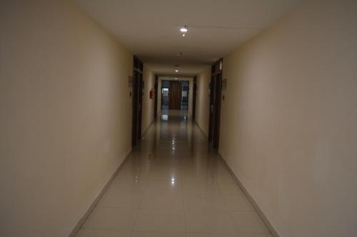 an empty hallway with white walls and tile floors at Hotel Ambicas Grand in Visakhapatnam