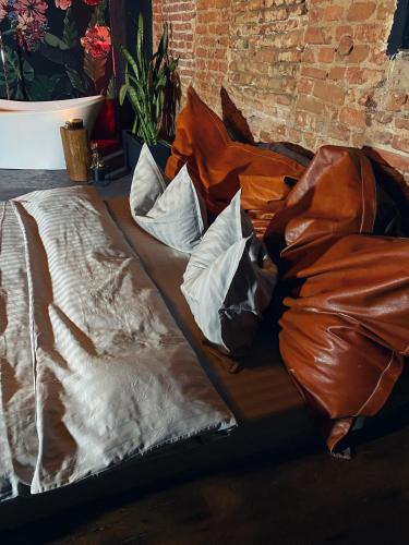 a bed with brown sheets and pillows next to a brick wall at World Studio 5 in Sibiu