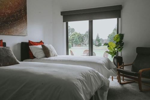 2 camas en una habitación con ventana y silla en Hillcrest - Daylesford Region, en Lyonville