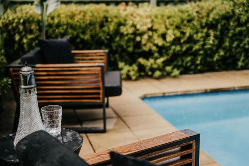 a bottle of wine sitting on a table next to a pool at Istana Lodge - Daylesford Region in Musk Vale