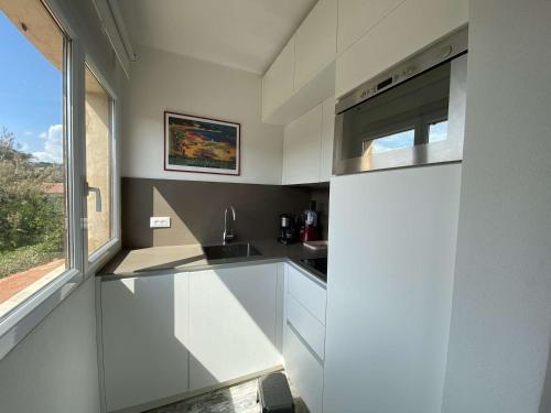 une cuisine avec des armoires blanches et une fenêtre dans l'établissement Sainte-Maxime : studio 2 pers refait à neuf avec clim, jardin et parking - FR-1-226-299, à Sainte-Maxime