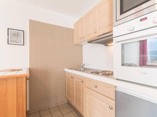- une cuisine avec des placards en bois et un four micro-ondes blanc dans l'établissement Apt 2P 4-6 Pers Briançon Proche Pistes, Balcon, TV, Cuisine Équipée, Animaux Admis - FR-1-330C-17, à Briançon