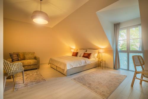 um quarto com uma cama, uma cadeira e uma janela em Arkady Hof Hotel em Stupava