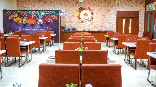 a dining room with tables and chairs and a chalkboard at Hotel Ambicas Grand in Visakhapatnam