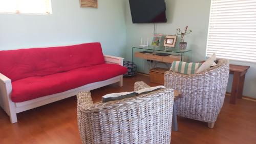 a living room with a red couch and two chairs at Rooftops in Bredasdorp