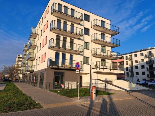 a tall white building with balconies on a street at Chillout Airport Apartment KL33 - Free parking in Warsaw