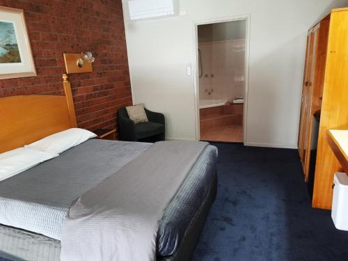 a bedroom with a bed and a brick wall at Abbotswood Motor Inn in Geelong