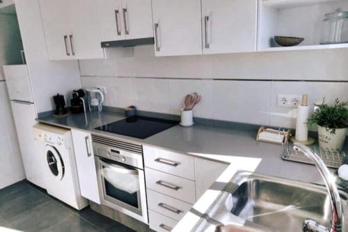 a kitchen with a sink and a stove top oven at Precioso apartamento en el Faro de Cullera in Cullera
