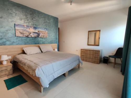een slaapkamer met een bed en een schilderij aan de muur bij Sahariana Sand in Marsaskala