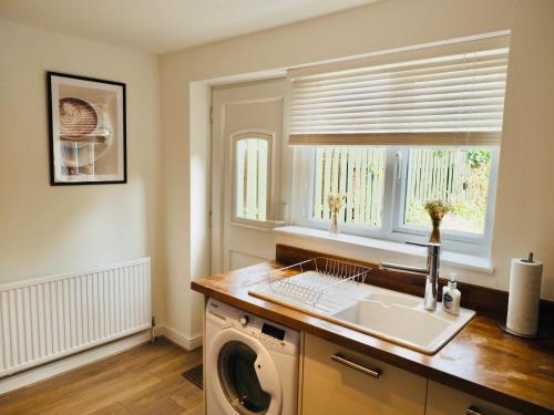 a kitchen with a washing machine and a window at Free Parking 2 Bed With Garden, Fibre Wi-Fi & Netflix in Taunton