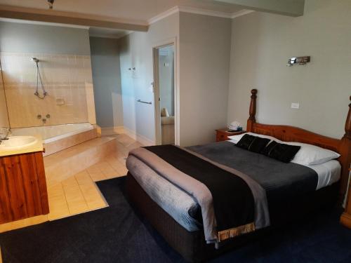 a bedroom with a large bed and a bath tub at Abbotswood Motor Inn in Geelong