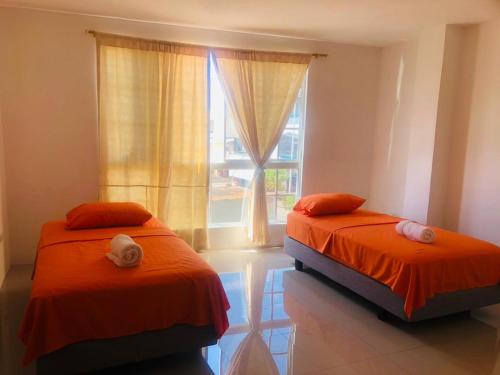 twee bedden in een kamer met een raam bij Pelican House in Puerto Baquerizo Moreno