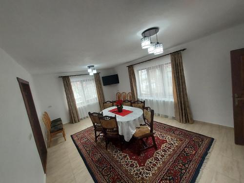 a dining room with a table and chairs on a rug at Casa Elena in Ceahlău