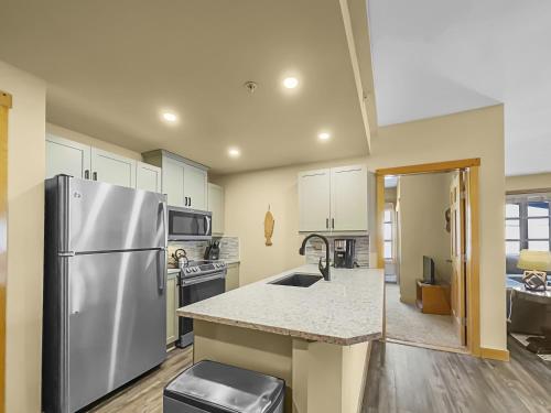 a kitchen with a stainless steel refrigerator and white cabinets at PP403 Passage Point condo in Copper Mountain