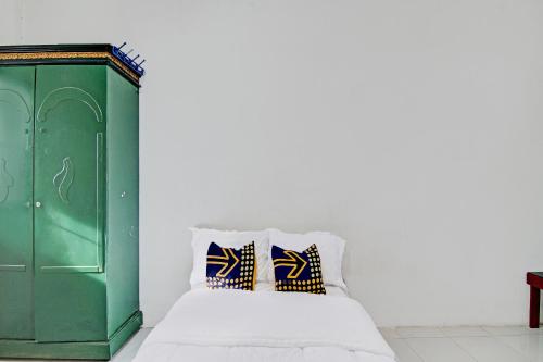 a bed with a green cabinet and two pillows at SPOT ON 91950 Guest House TekNong Syariah in Bangkinang