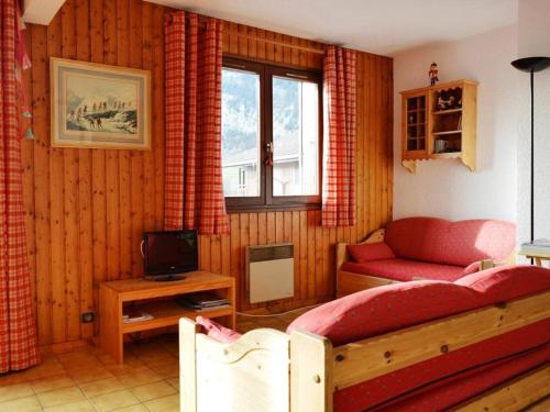 un salon avec un canapé rouge et une télévision dans l'établissement Appartement skis aux pieds 6 pers, balcon sud, garage, ménage inclus, 3* - FR-1-241-171, au Grand-Bornand