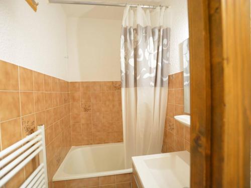 a bathroom with a tub and a shower curtain at Studio Le Grand-Bornand, 1 pièce, 4 personnes - FR-1-241-173 in Le Grand-Bornand