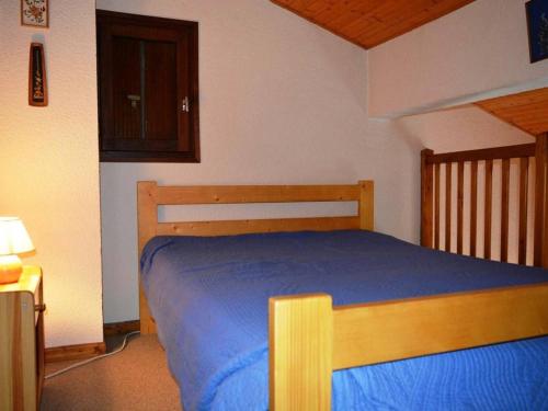 a bedroom with a wooden bed with a blue blanket at Appartement Le Grand-Bornand, 1 pièce, 4 personnes - FR-1-241-170 in Le Grand-Bornand