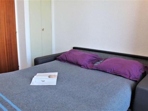 リスルにあるAppartement Risoul, 1 pièce, 4 personnes - FR-1-330-288の紫色の枕と本が付いたベッド