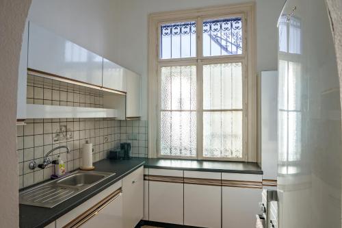 une cuisine blanche avec un évier et une fenêtre dans l'établissement Vienna Living Apartments - Gumpendorfer Straße, à Vienne