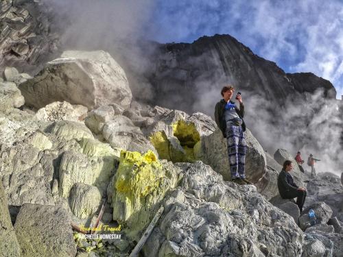 a man standing on a mountain talking on a cell phone at Nachelle Homestay in Berastagi