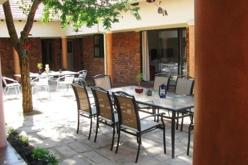 a patio with a table and chairs and a tree at Guesthouse Serenity in Hartbeespoort