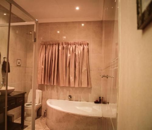 łazienka z wanną, toaletą i umywalką w obiekcie Guesthouse Serenity w mieście Hartbeespoort