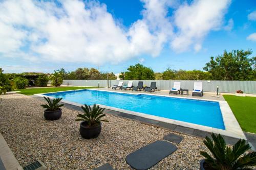 a swimming pool with chairs and plants in a yard at By the sea, Algarve in Galé