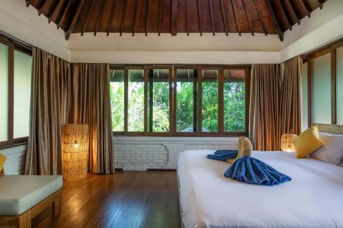 a bedroom with a large white bed with windows at Villa Lunacasa, Modern Comfort in Balinese Style, 500m to beach in Seminyak