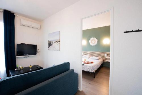 een woonkamer met een bank en een slaapkamer bij appartement n2 centre village, clim, parking gratuit in Aigues-Mortes