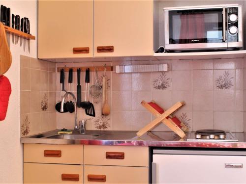 une cuisine avec un évier et un micro-ondes dans l'établissement Appartement cosy avec 5 couchages, centre de station Risoul 1850, proche remontées et commerces - FR-1-330-162, à Risoul