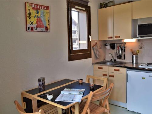 une cuisine avec une table et des chaises et une table et un comptoir dans l'établissement Appartement cosy à Risoul 1850 - 4 couchages, proche remontées mécaniques et commerces - FR-1-330-220, à Risoul