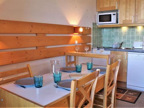une cuisine avec une table et quatre chaises et une cuisine avec un four micro-ondes dans l'établissement Studio cabine 4 pers, pied de pistes, animaux acceptés – Risoul 1850 - FR-1-330-221, à Risoul