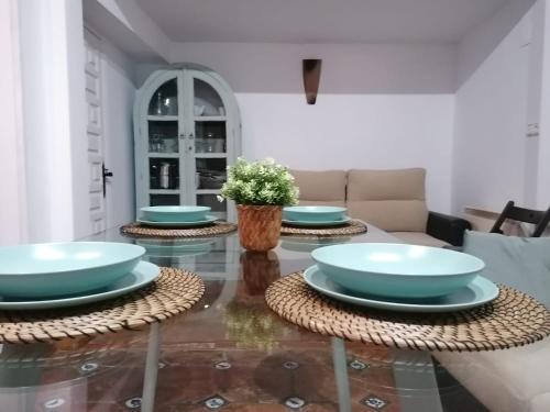une salle à manger avec des bols bleus sur une table en verre dans l'établissement Apartamentos miradores de granada, à Grenade
