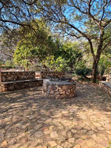 a stone patio with two benches and a tree at Guesthouse Serenity in Hartbeespoort