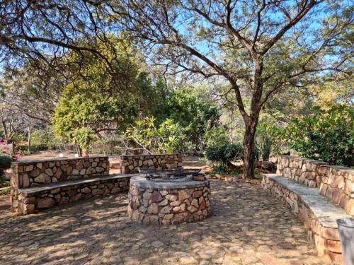 a park with a stone wall and benches and a tree at Guesthouse Serenity in Hartbeespoort