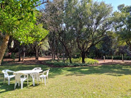 a table and chairs in a park with trees at Guesthouse Serenity in Hartbeespoort